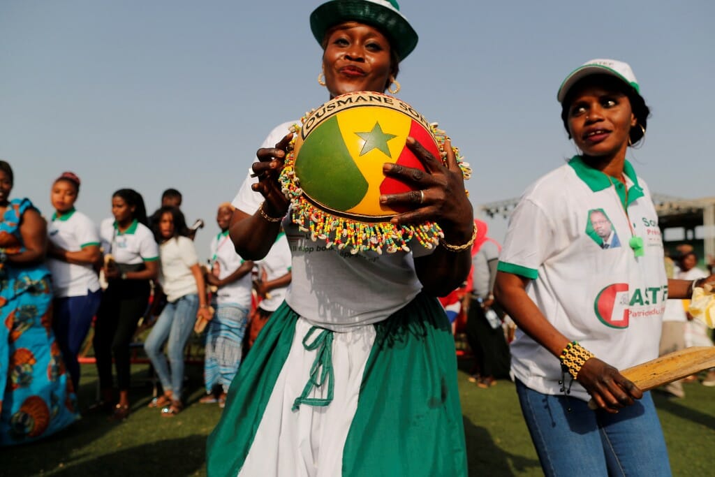 Supporters dance as they await the arrival of presidential candidate Ousmane Sonko at a campaign rally in Pikine