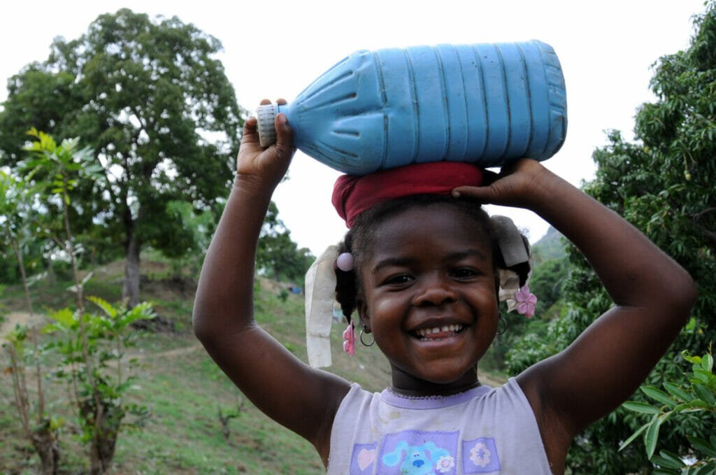 An innocent Haitian little girl displays a beautiful smile in the middle of the chaos around her.