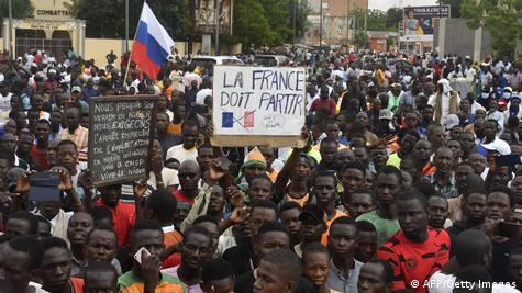 Pro-coup demonstrators carry a Russian flag and banner saying France Must Leave