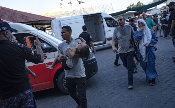 A Palestinian man carries a wounded girl to a hospital