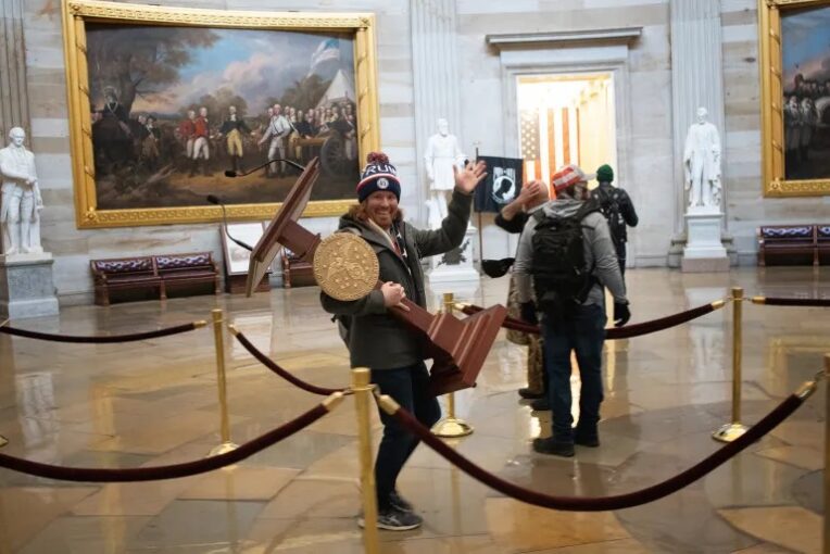 An insurrectionist grabs the lectern of then-Speaker Nancy Pelosi on January 6, 2021