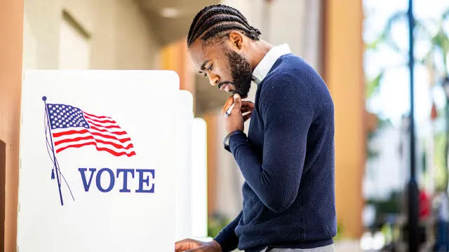 Black man submits his vote at a polling station. Photograph courtesy of Unsplash.