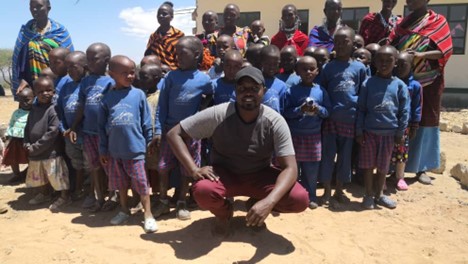 Paul Ole Leitura (Center), Executive Director of Mulika Africa posing with a number of Maasai community members and children that he has been helping