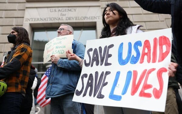 Demonstrators outside of the U.S. Agency for International Development headquarters in Washington on Monday. Senior officials have been suspended, and hundreds of civil servants and contractors have been frozen out of its systems without warning. Credit...Tierney L. Cross for The New York Times.
