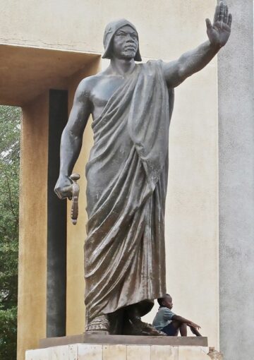 A statue of King Gbêhanzin, the last monarch of the Danxomê kingdom who dragged the French colonizers into a two-year war to save his kingdom from being colonized. The magnificent monument is set in the heart of Agbomê (called Abomey by the French invaders who didn’t know better), the capital city of the Danxomê kingdom, a stonethrow away from Djimê, where Gbêhanzin’s palace once stood.