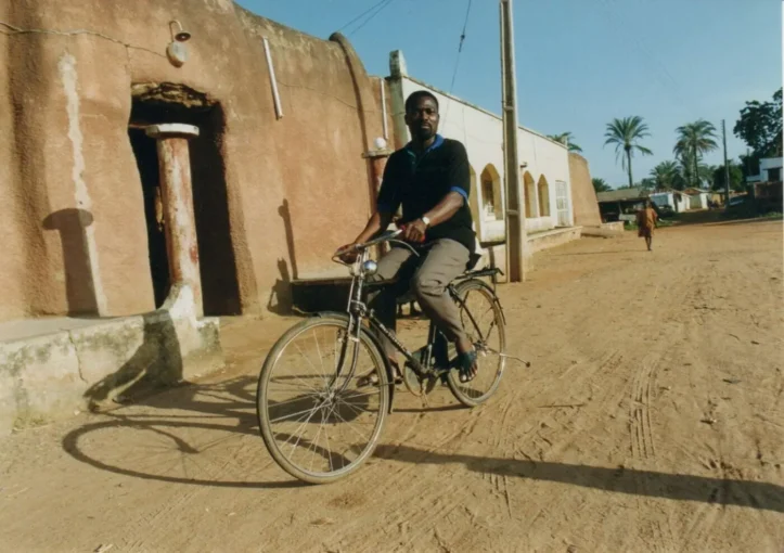 The African founder/publisher Soumanou Salifou enjoys a bicycle ride in the historic village of Babangani, on the outskirts of Bauchi, in 2000.